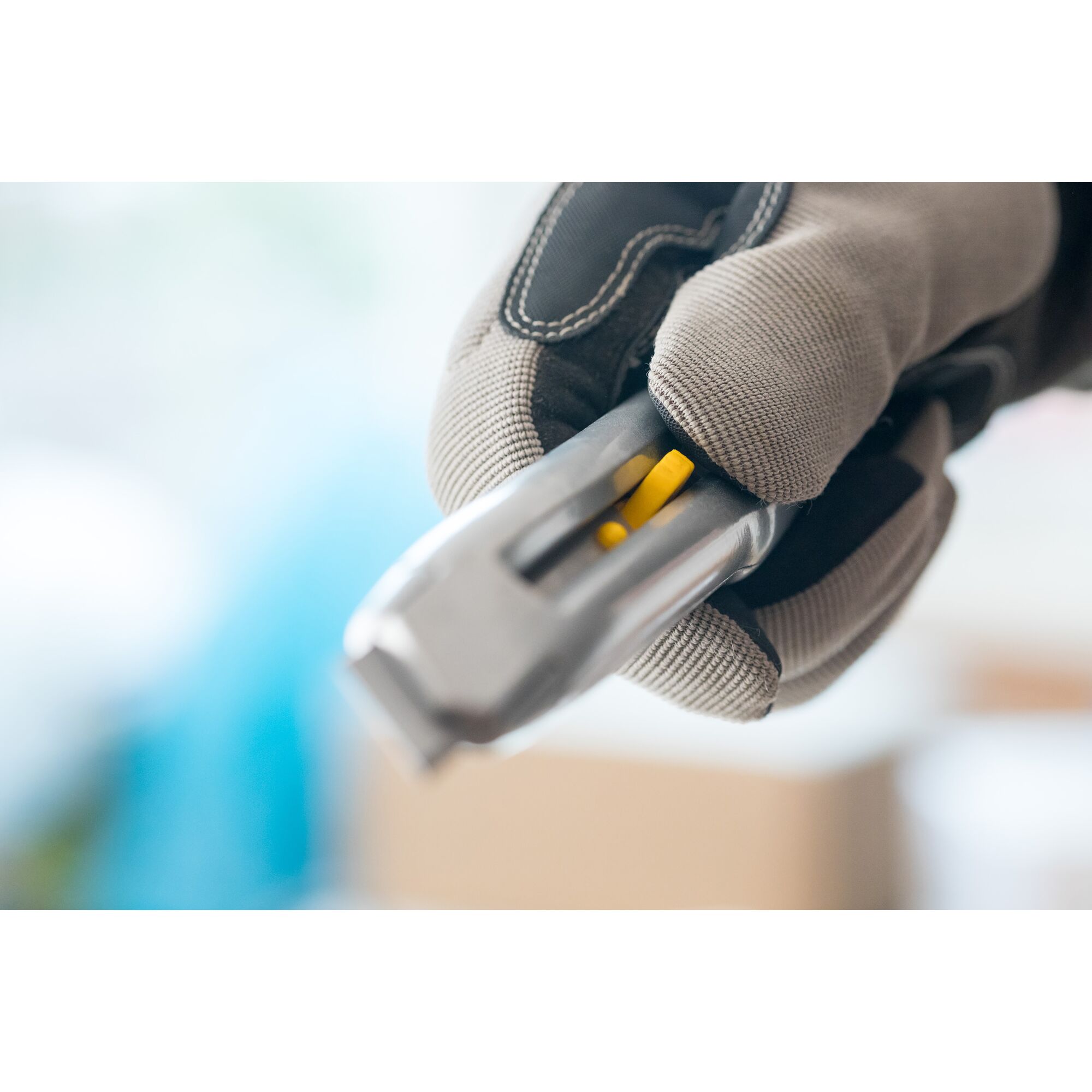 STANLEY 0-10-018 utility knife in gloved hand, close-up, highlighting yellow slider.