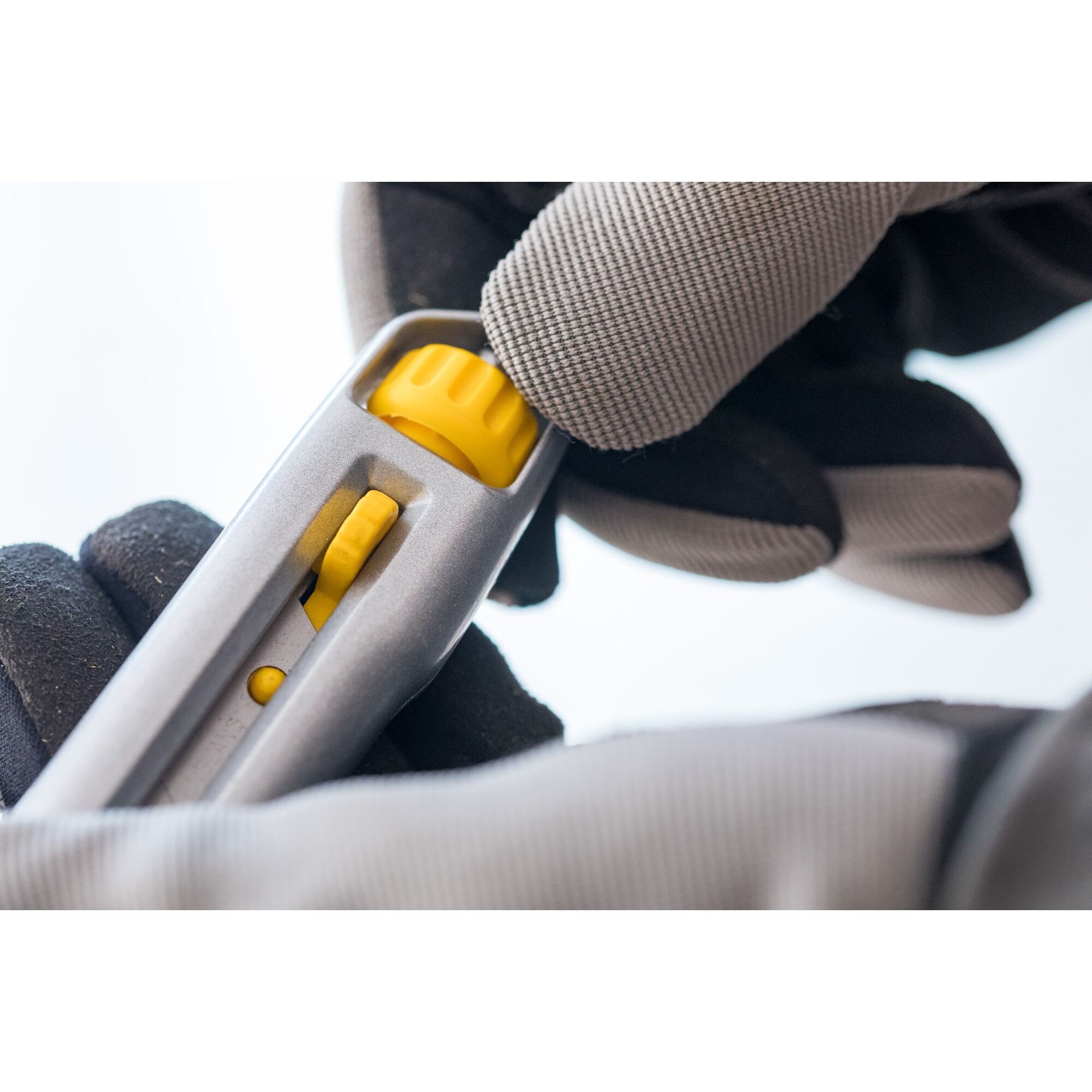 STANLEY 0-10-018 utility knife close-up, showing yellow adjustment wheel, held by gloved hand.