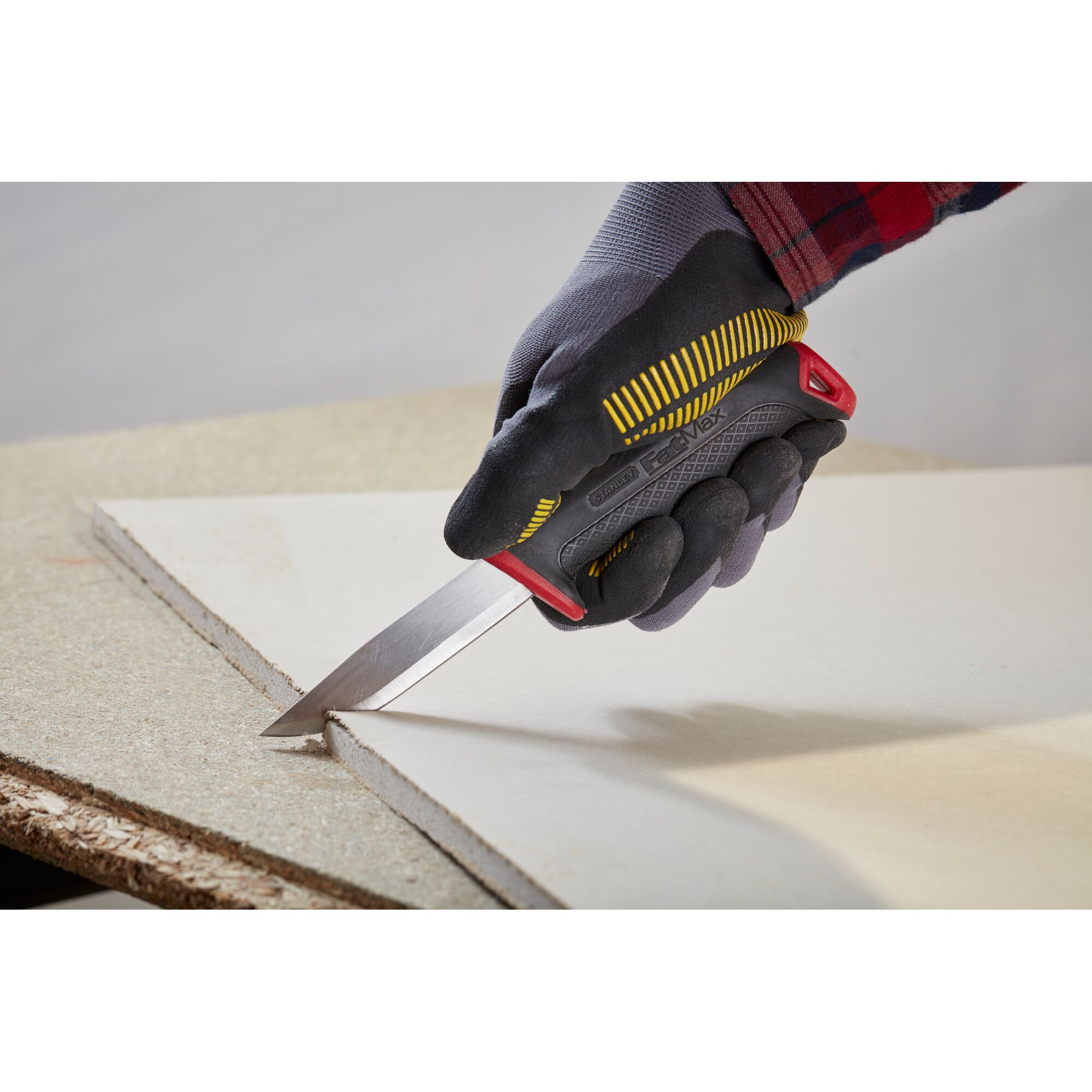 Photo of STANLEY 0-10-231 utility knife cutting drywall held by a gloved hand.