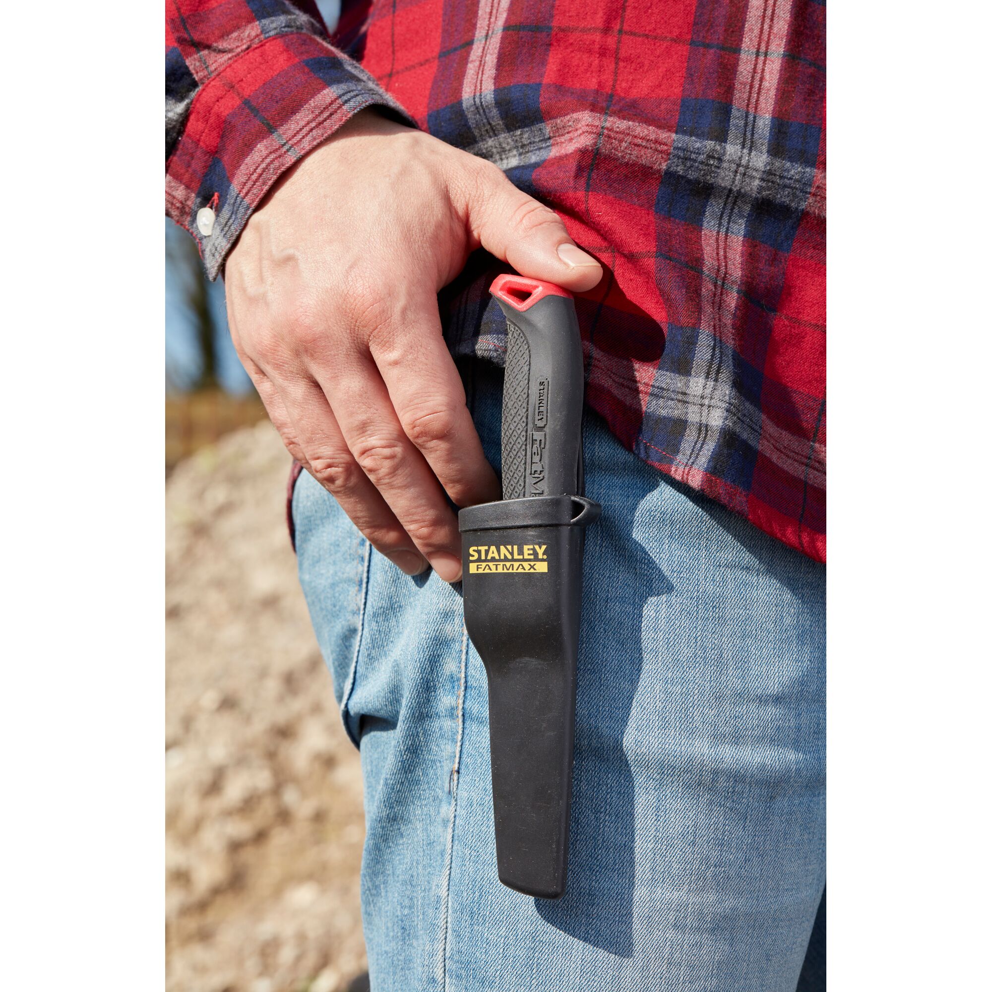 STANLEY 0-10-231 utility knife in black sheath clipped to jeans, person wearing red plaid shirt.