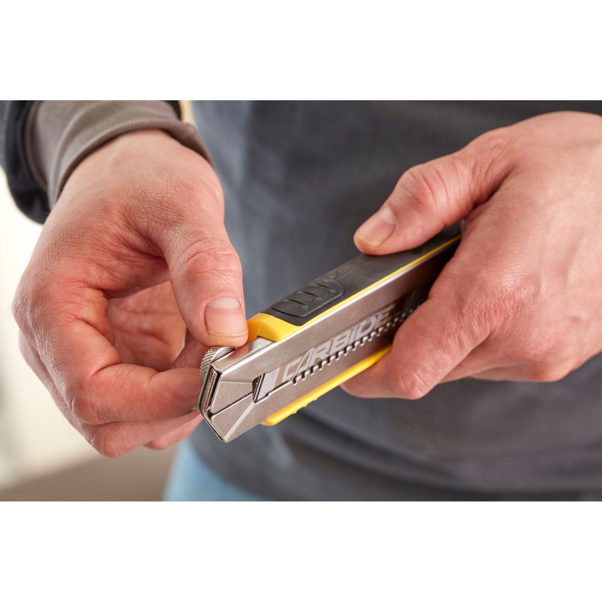 Photo of hands holding a STANLEY 0-10-481 snap-off utility knife, close-up angle showing blade adjustment.