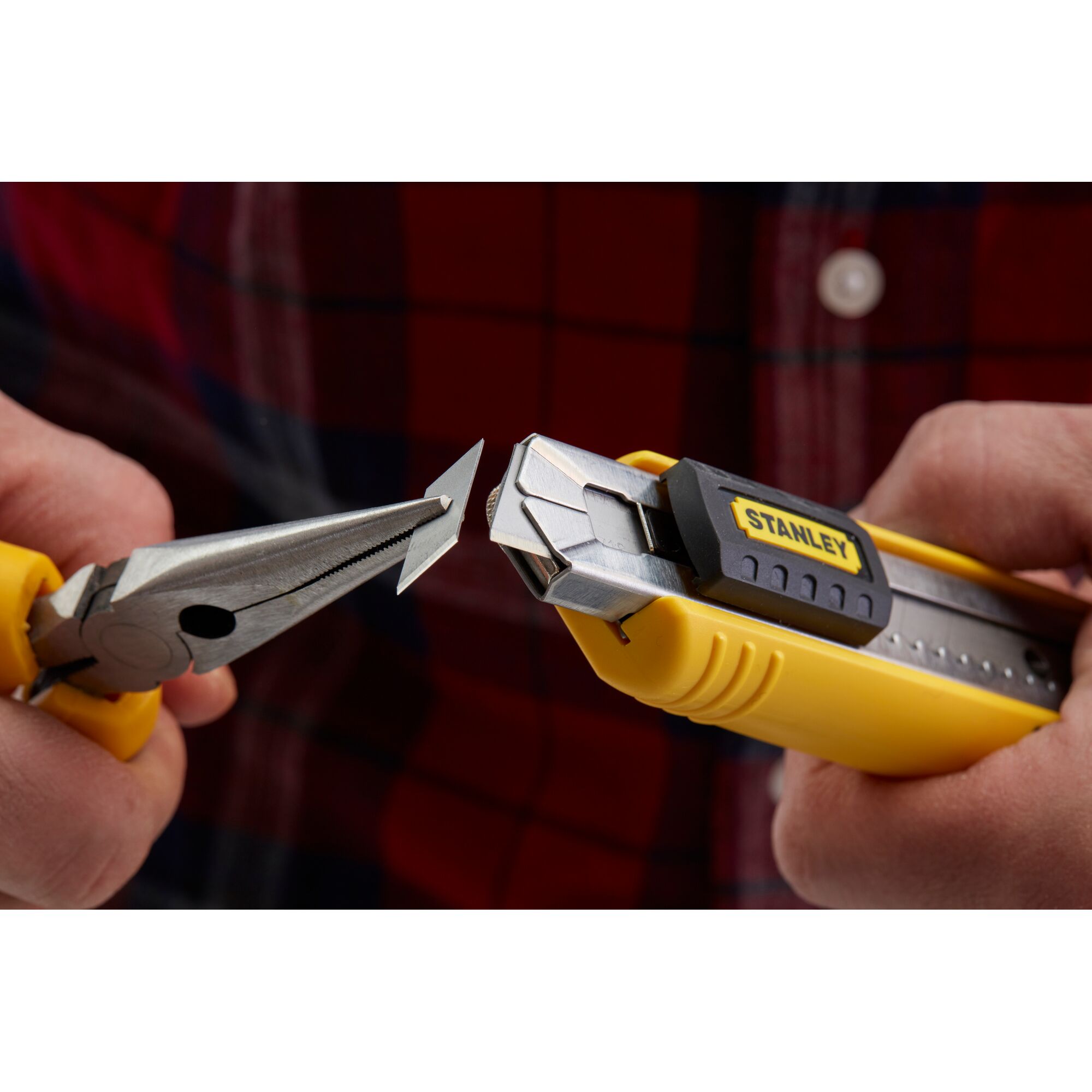 Photo of STANLEY 0-10-481 utility knife with yellow handle, blade held by pliers, close-up in use.