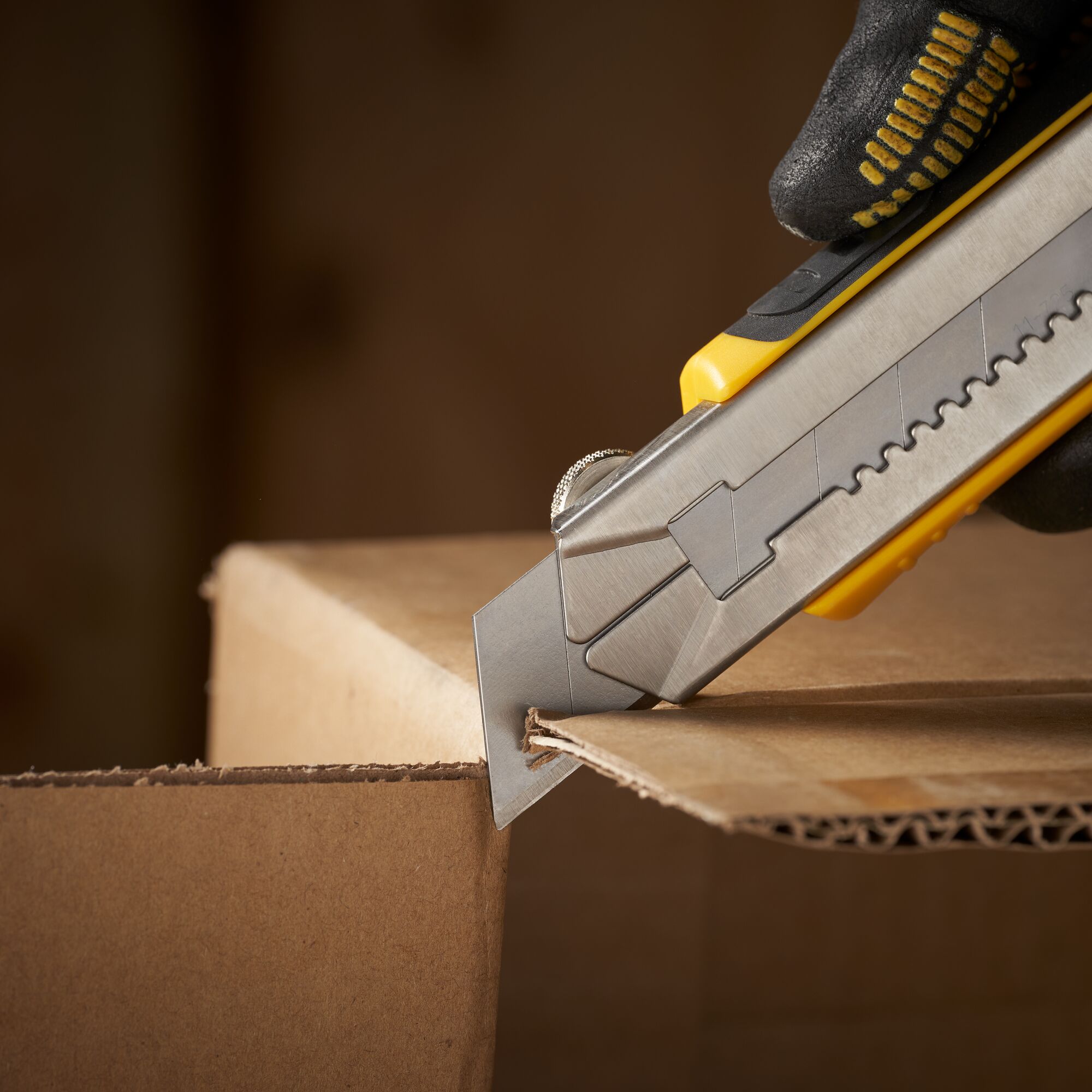 STANLEY 0-11-325 utility knife cutting cardboard box close-up, photography of hand holding tool.