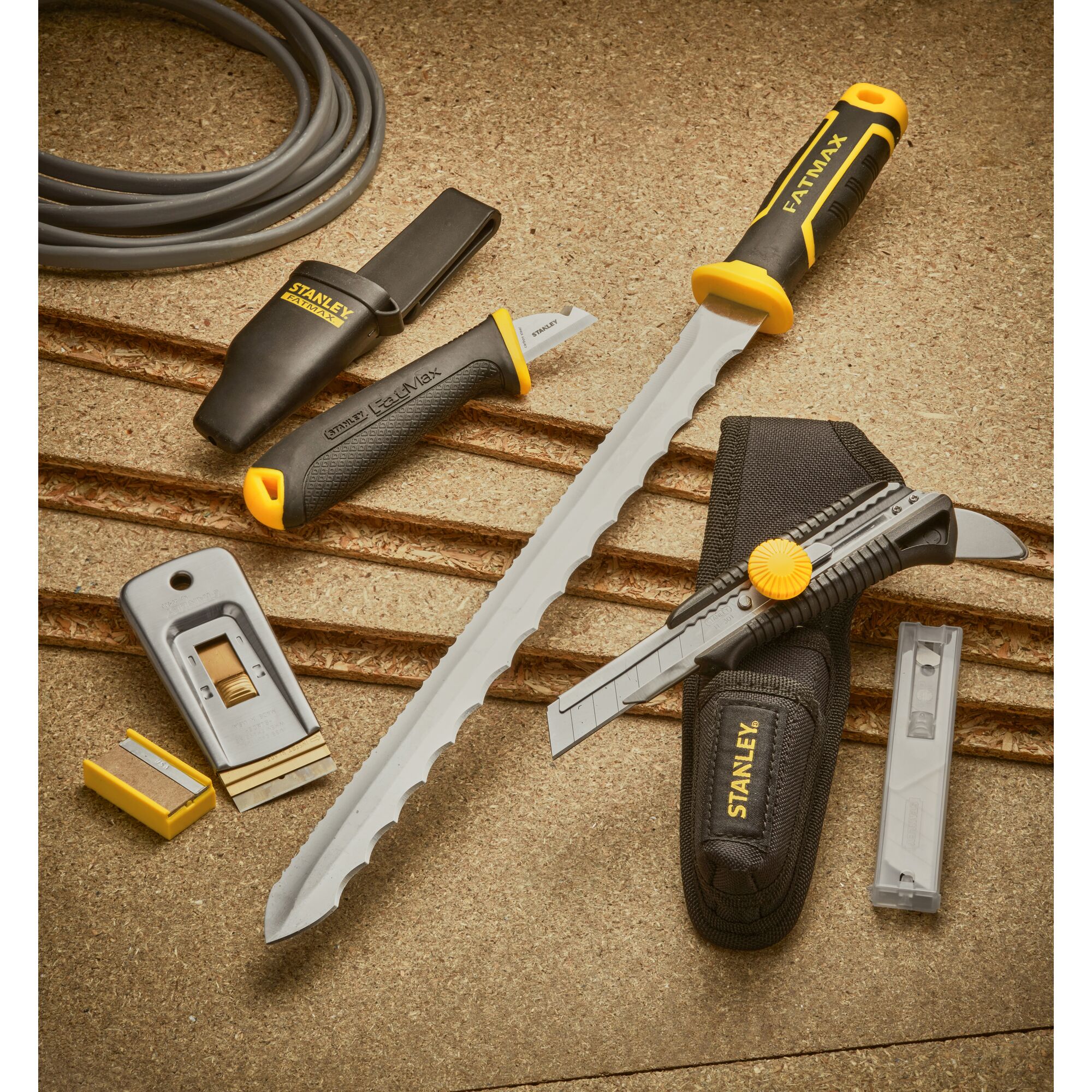STANLEY 0-28-500 set of hand tools with cutting knives, a rasp, utility blades, and black-yellow handles on a tan surface.