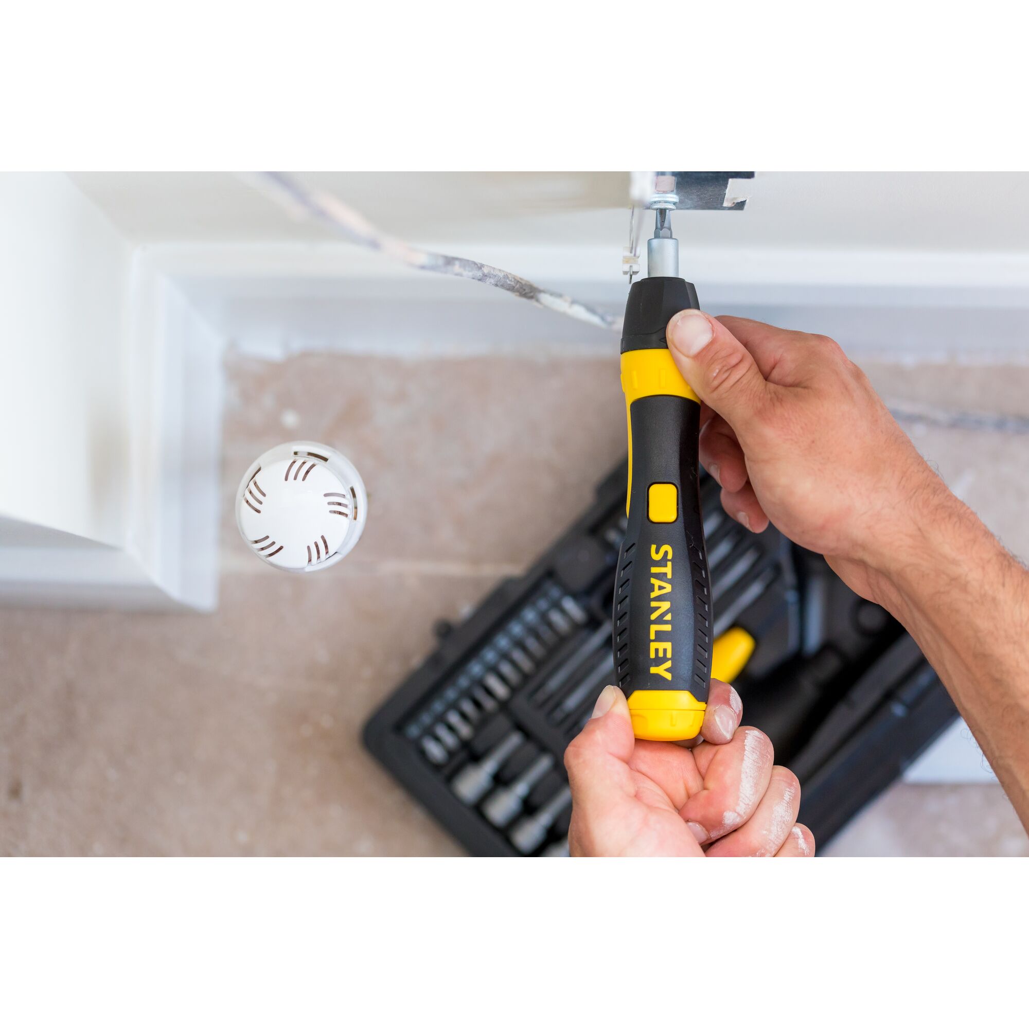 STANLEY 0-63-038 ratcheting screwdriver set in use, black and yellow handle, top view, toolkit in background.