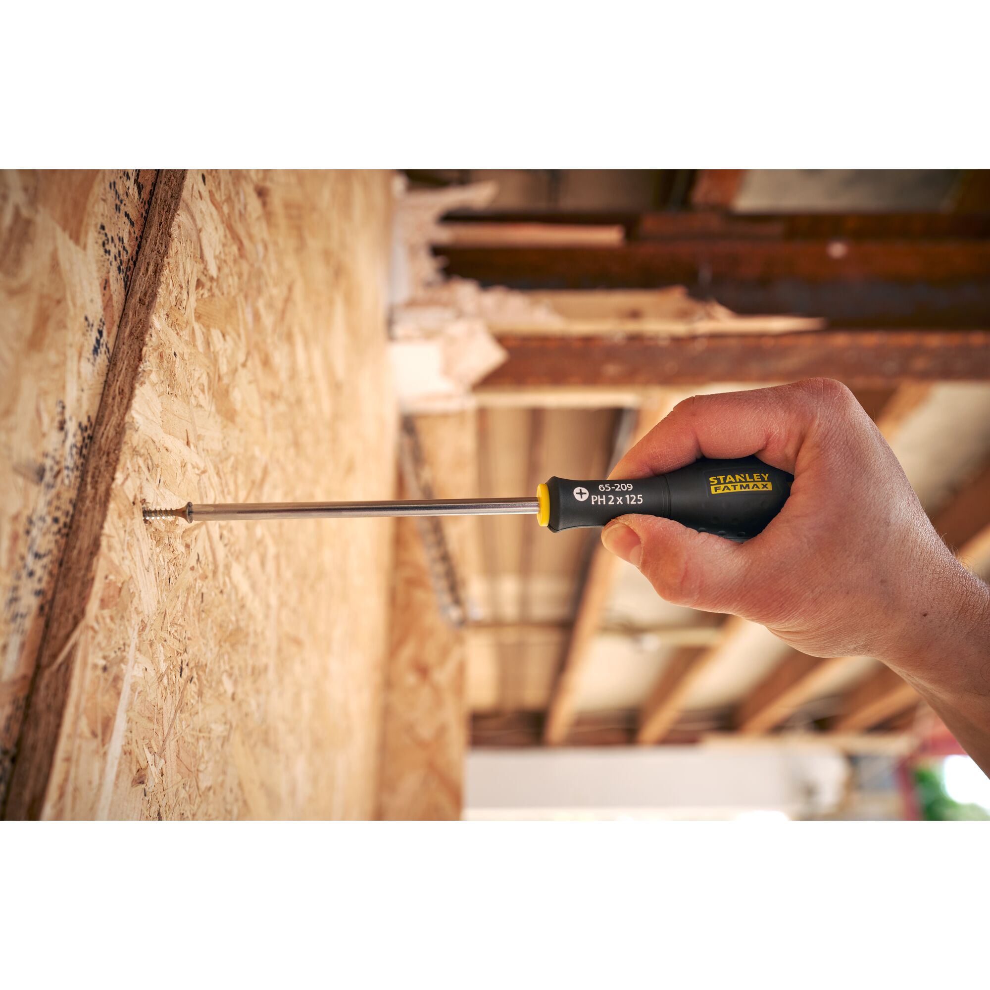 Stanley 0-65-209 screwdriver used on wood panel, close-up view of black and yellow handle.