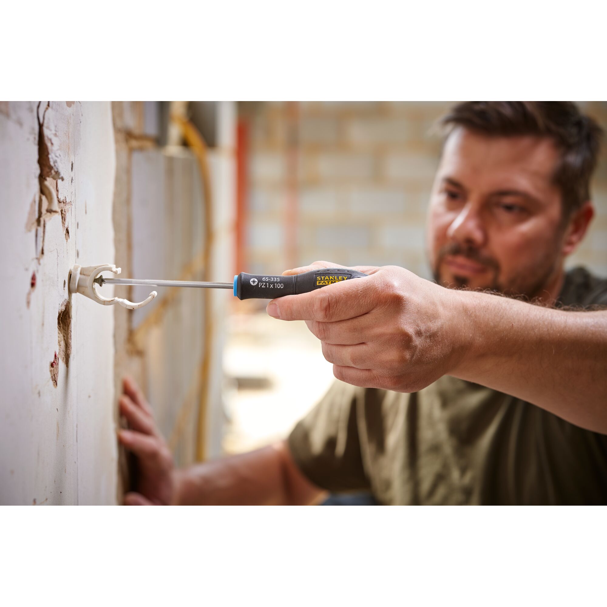 Stanley 0-65-335 screwdriver in use, close-up of hand installing wall bracket, construction setting.