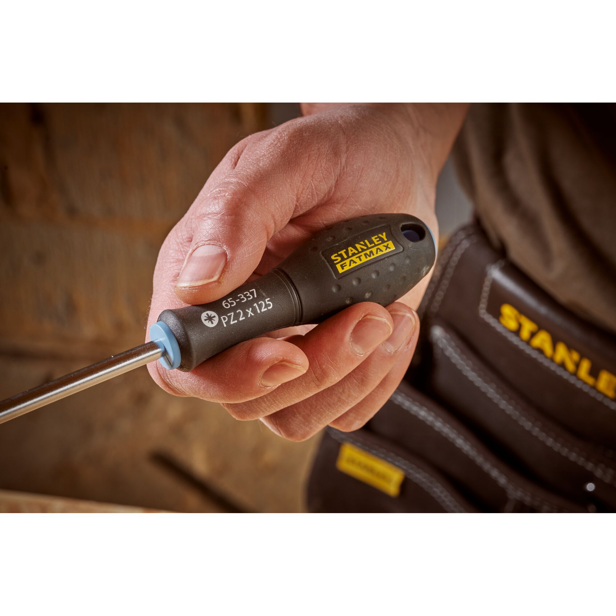 Photo of STANLEY 0-65-337 screwdriver with black handle and yellow logo, held in hand, close-up view.