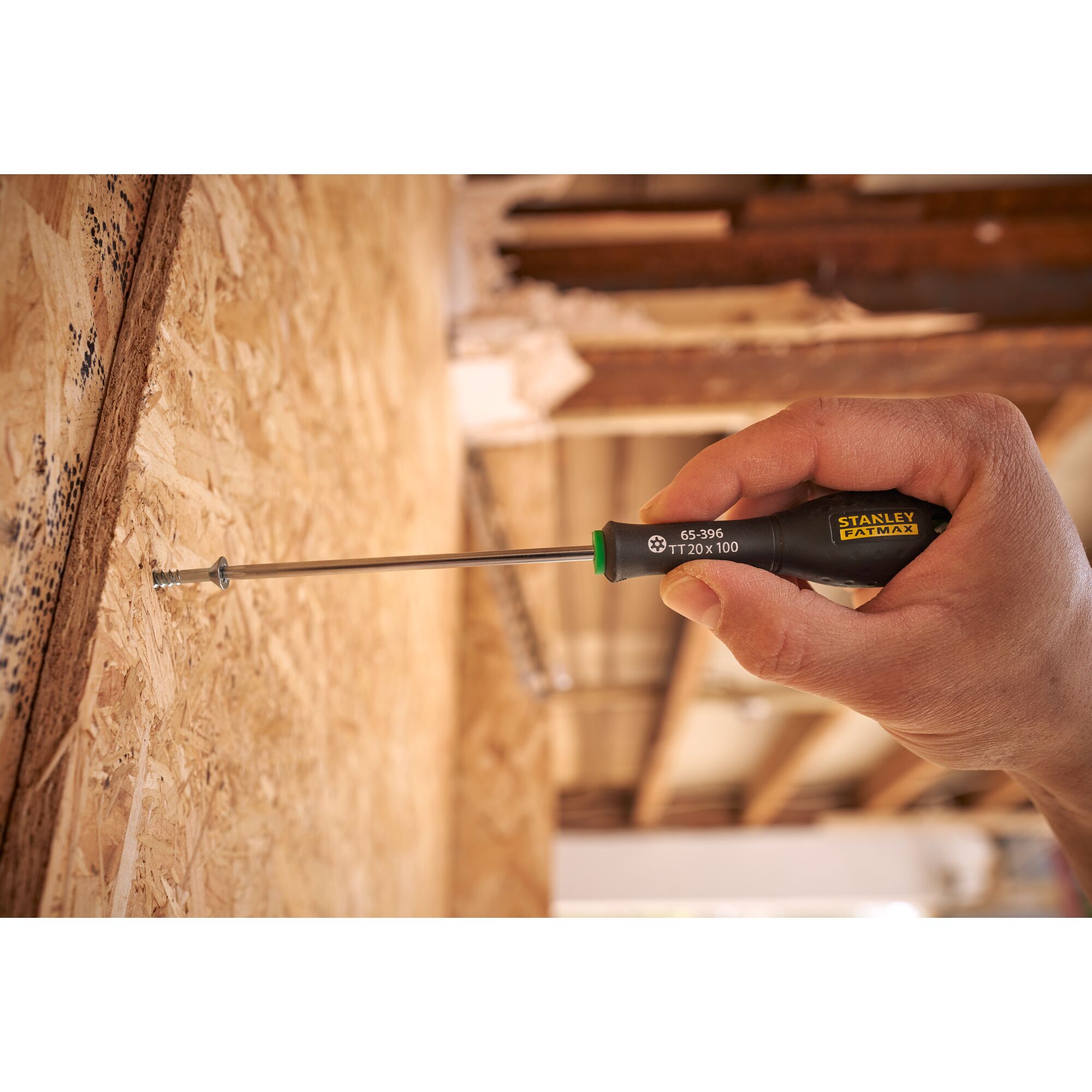 Stanley 0-65-396 screwdriver in use, black handle with yellow logo, tightening screw into wood surface.