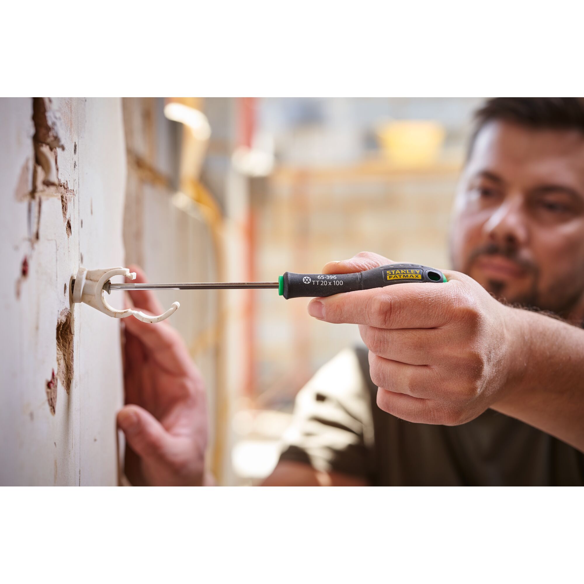 Photo of STANLEY 0-65-396 screwdriver being used to secure a wall bracket, close-up of hand and tool in action.