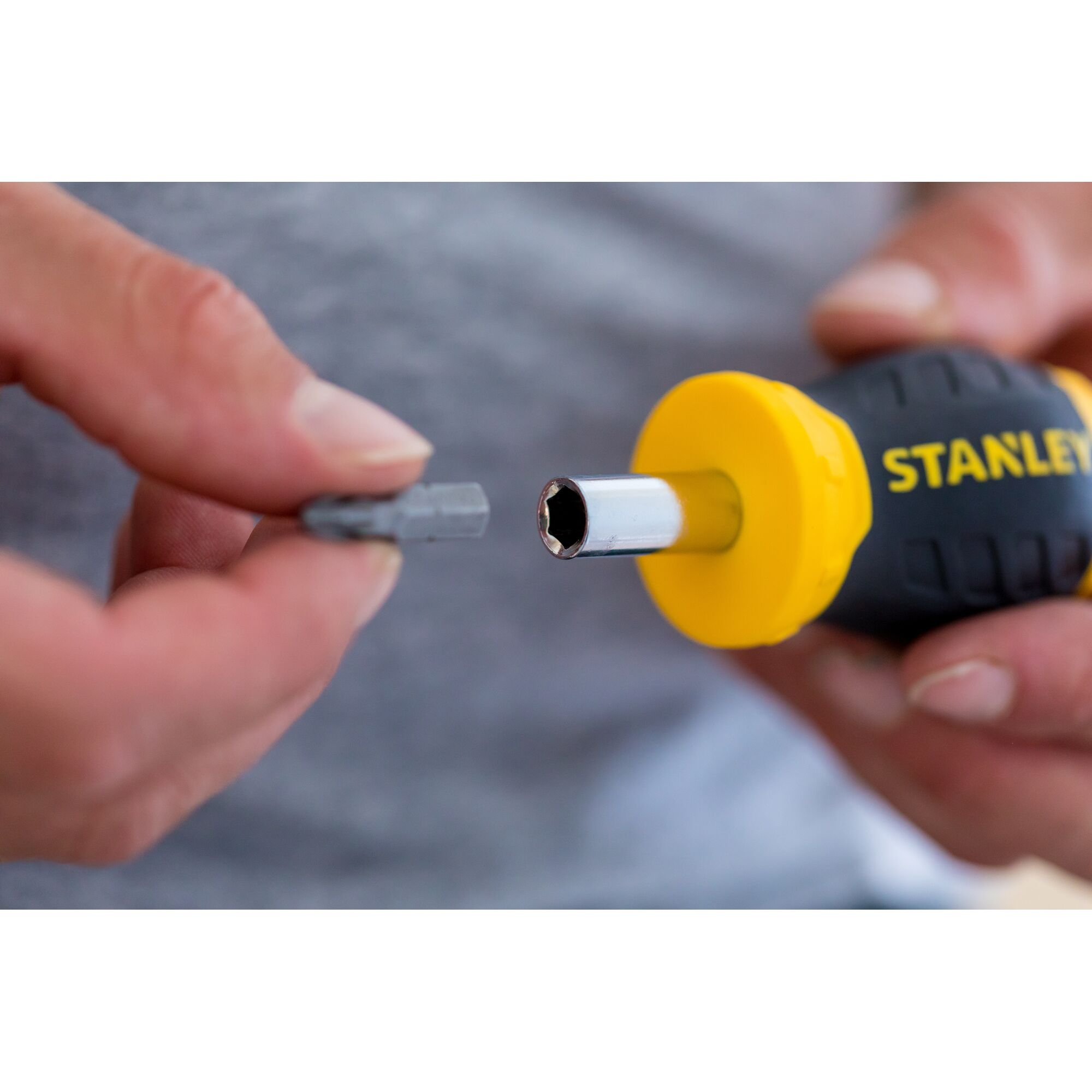 STANLEY 0-66-357 screwdriver handle with yellow accent and interchangeable bit held in hand, close-up.