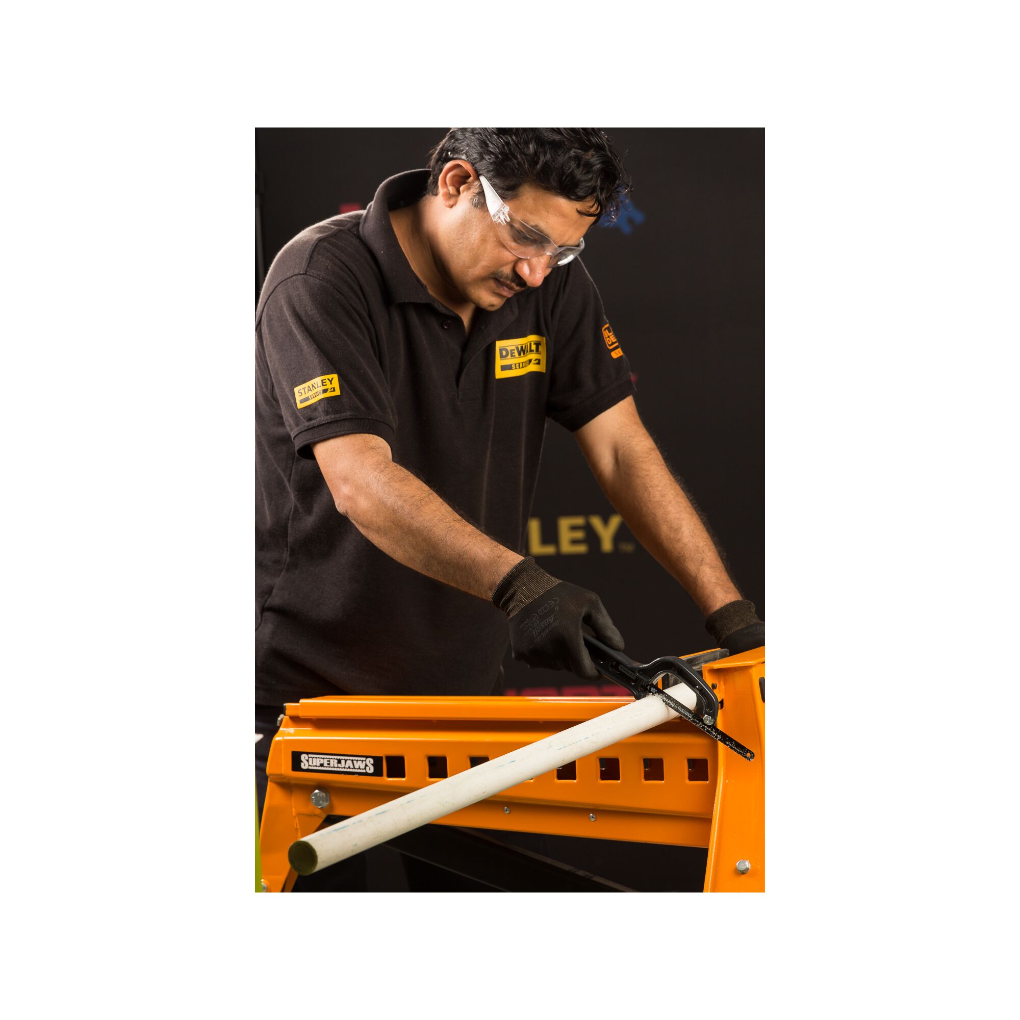 STANLEY 20-807 SuperHaws workbench holding white pipe, person wearing gloves and branded shirt.