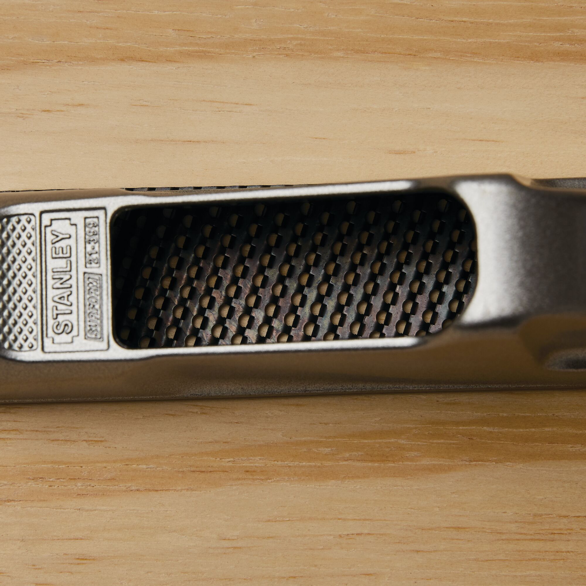 Stanley 21-399 metal rasp tool close-up on a wooden surface, showing textured handle and grating.