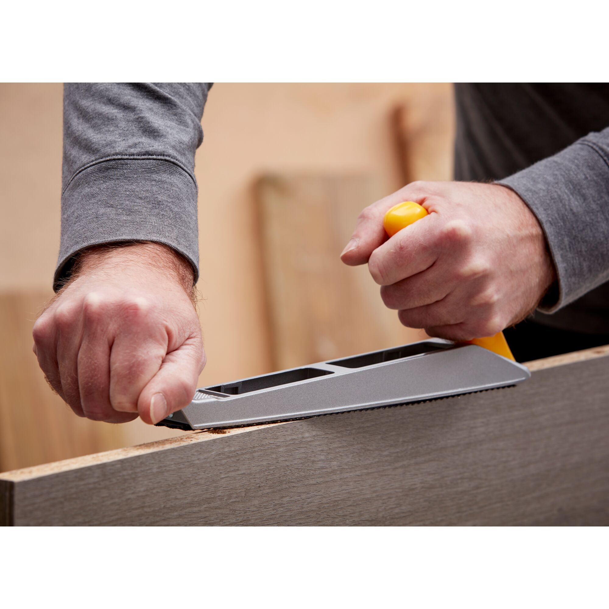 Photo of STANLEY 5-21-122 hand rasp tool shaping the edge of a wooden board, close-up of use in workshop.