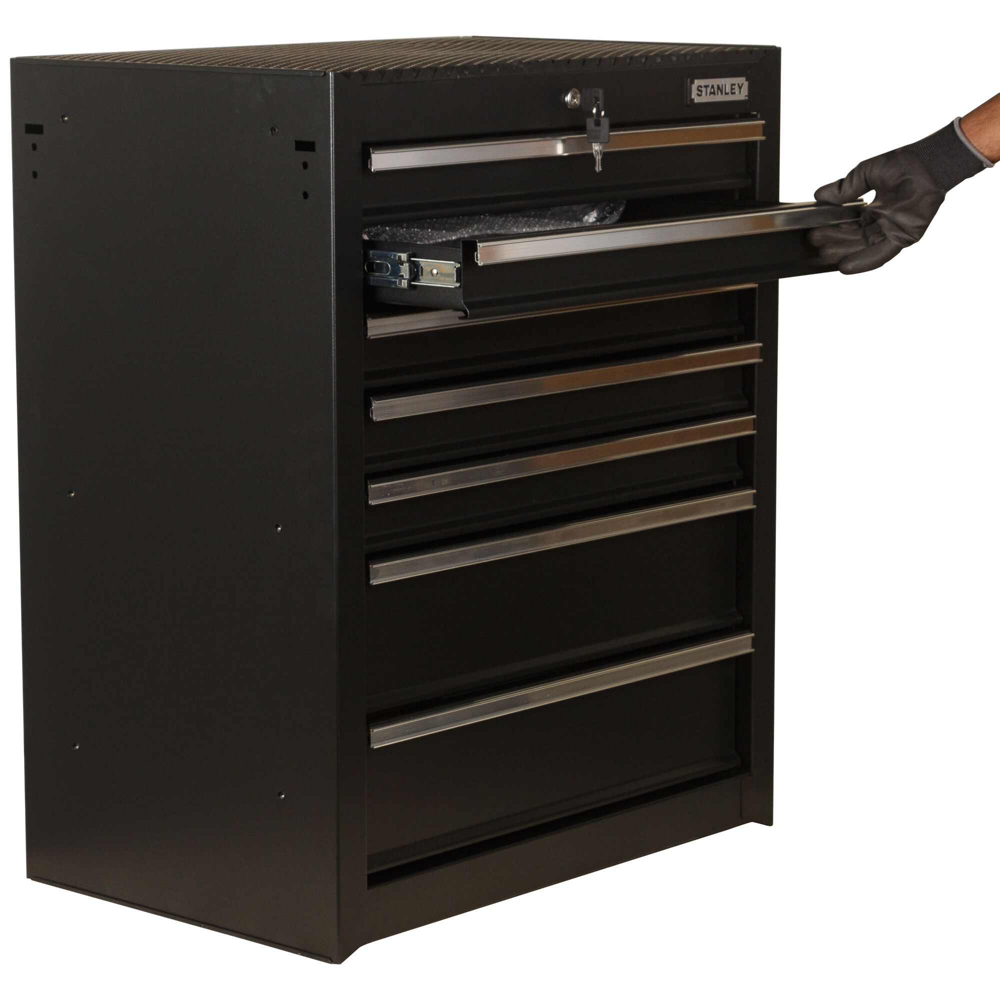 STANLEY 93-547-23ID black metal tool chest with seven drawers, side angle, one drawer partially open, gloved hand visible.