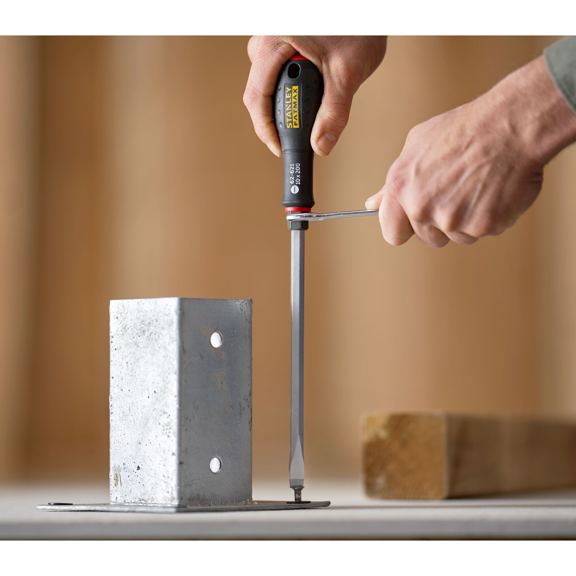 STANLEY FMHT0-62621 screwdriver used on a metal bracket, close-up with hands holding tool.