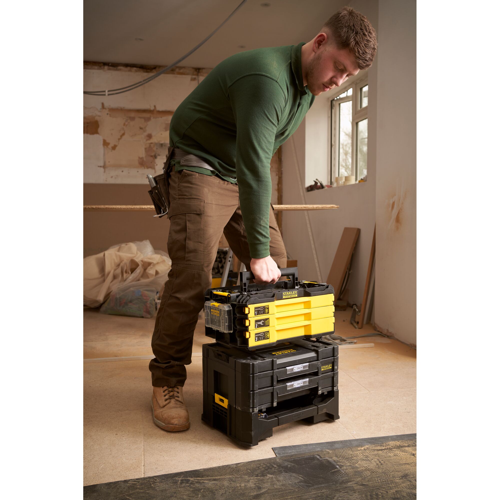STANLEY FMMT98107-1 tool storage stack, yellow and black, carried by person in workshop setting.