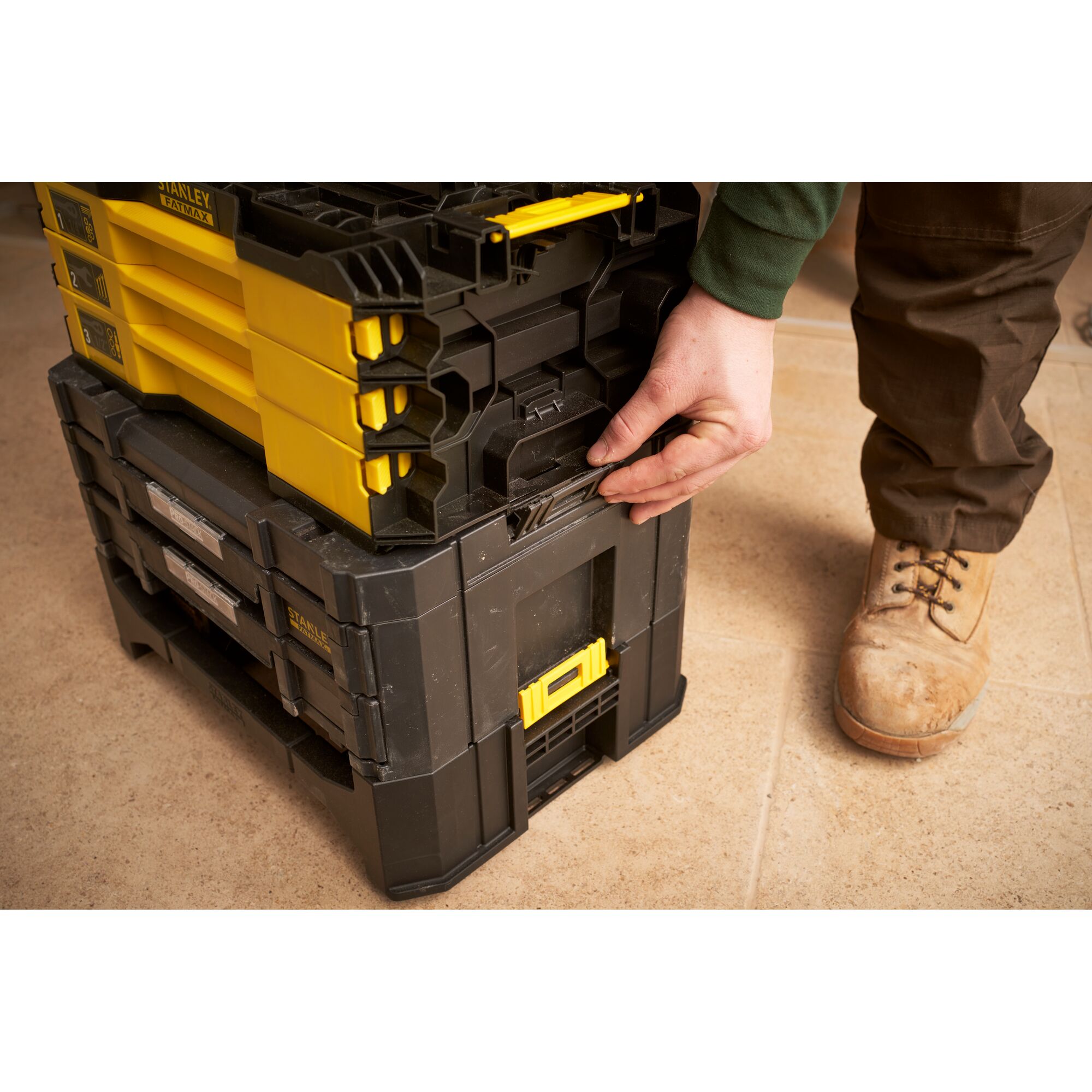 STANLEY FMMT98107-1 stackable toolboxes with yellow and black design, shown being latched together on tile floor.