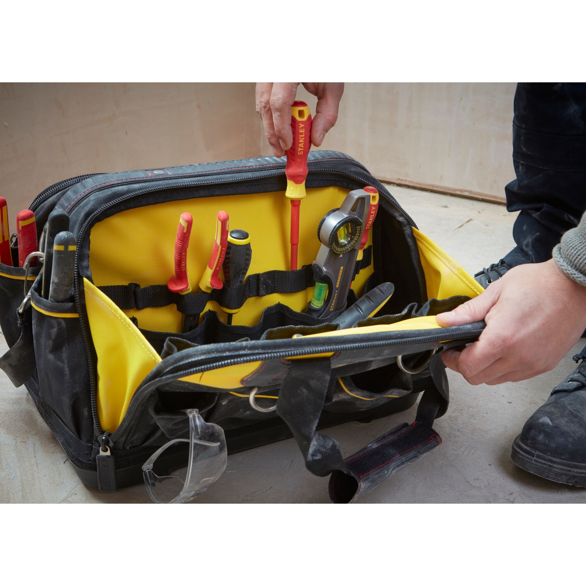 STANLEY FMST1-73607 tool bag with yellow interior, hand placing screwdriver, assorted tools visible.
