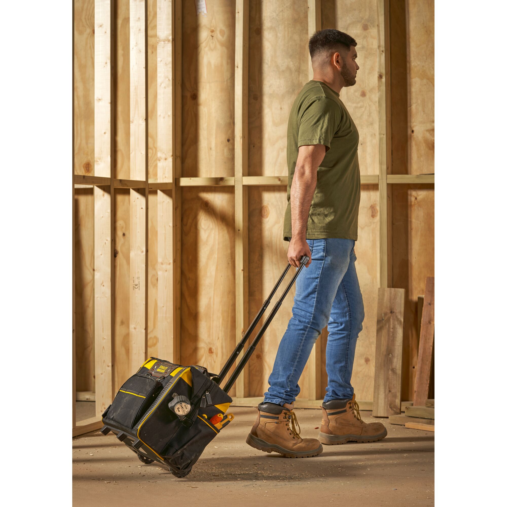 Photo of STANLEY FMST1-80148 rolling tool bag being pulled by person on construction site.