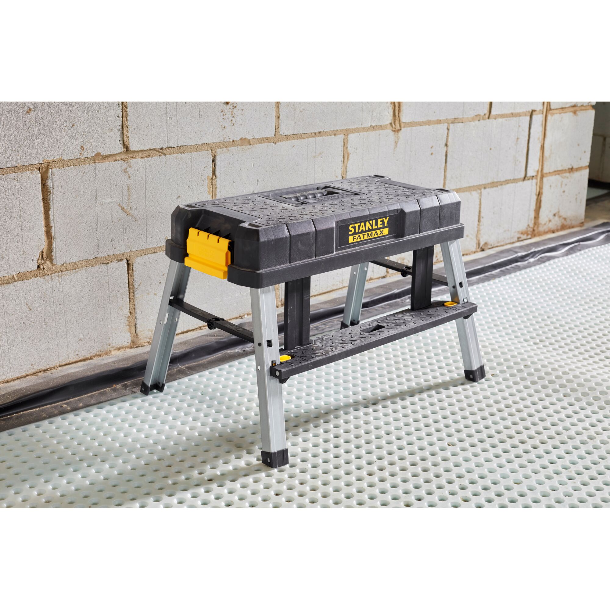 STANLEY FMST81083-1 step stool with black and yellow plastic top and metal legs, side angle, indoors.
