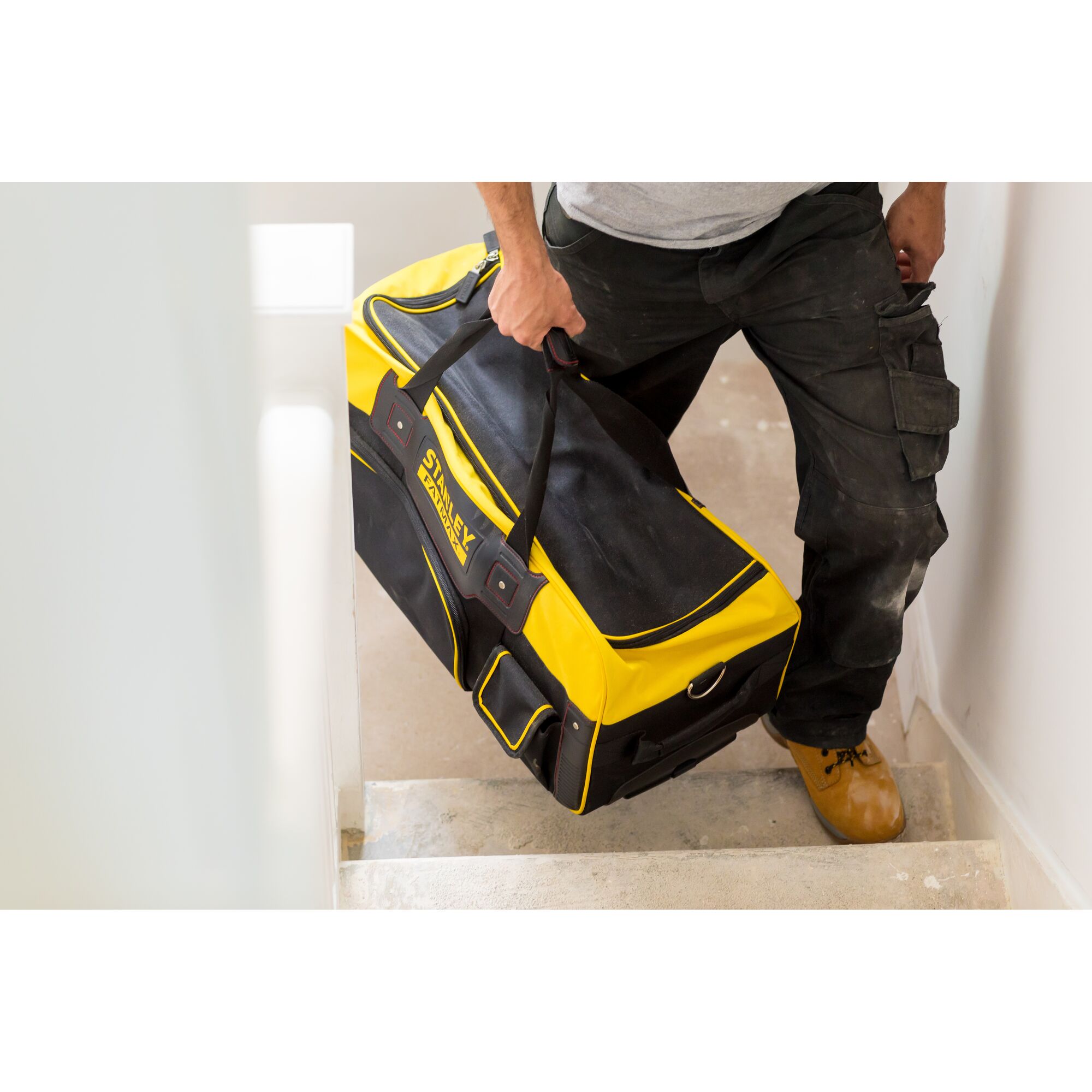 STANLEY FMST82706-1 yellow and black tool bag carried by person on staircase.
