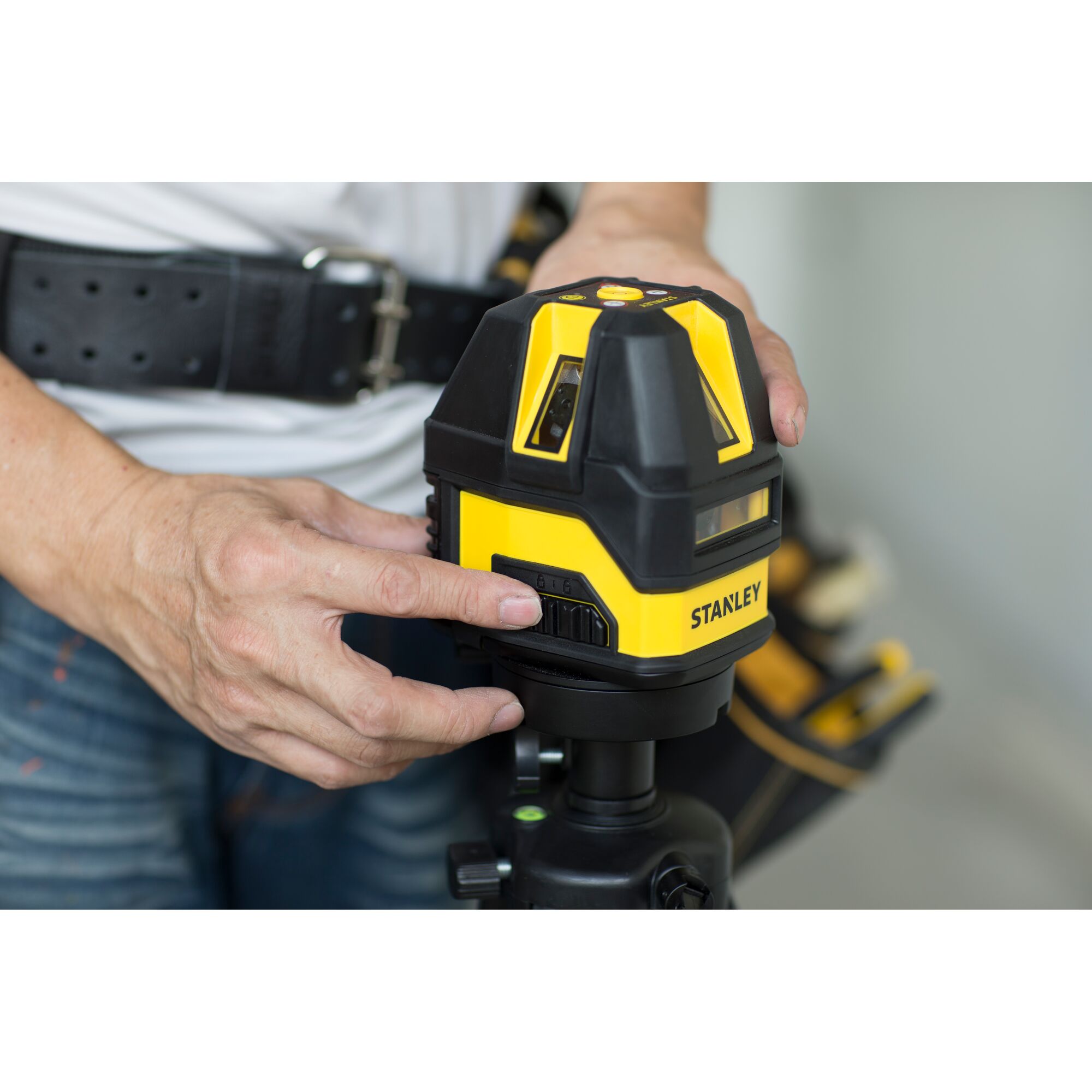 STANLEY STHT77513-8 laser level device held by person, close-up view, yellow and black housing.