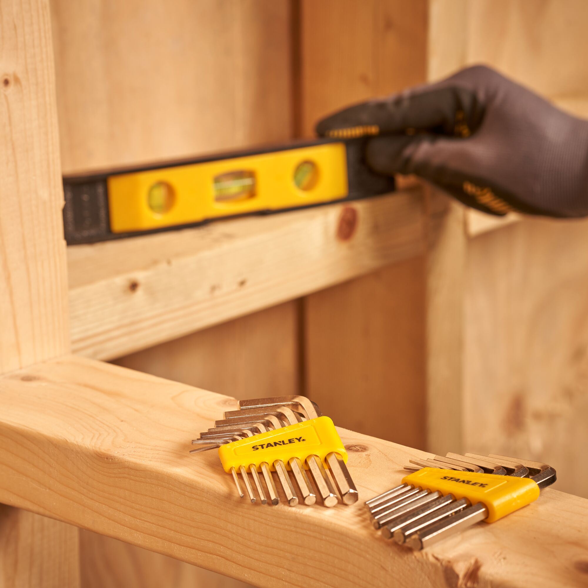 STANLEY STMT0-74101 hex key sets with yellow holders on wood in workshop setting, close-up.