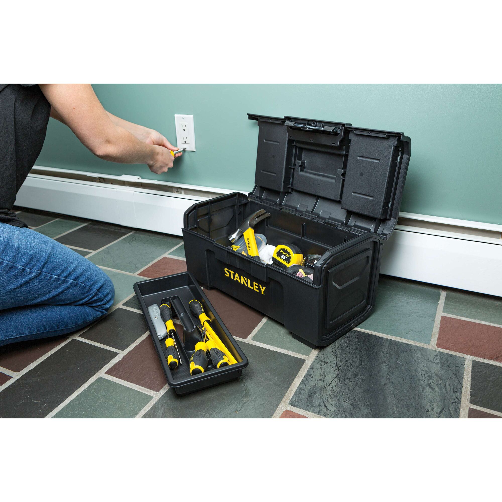 STANLEY STST19420 black toolbox with open lid showing tools, placed on floor next to person repairing outlet.