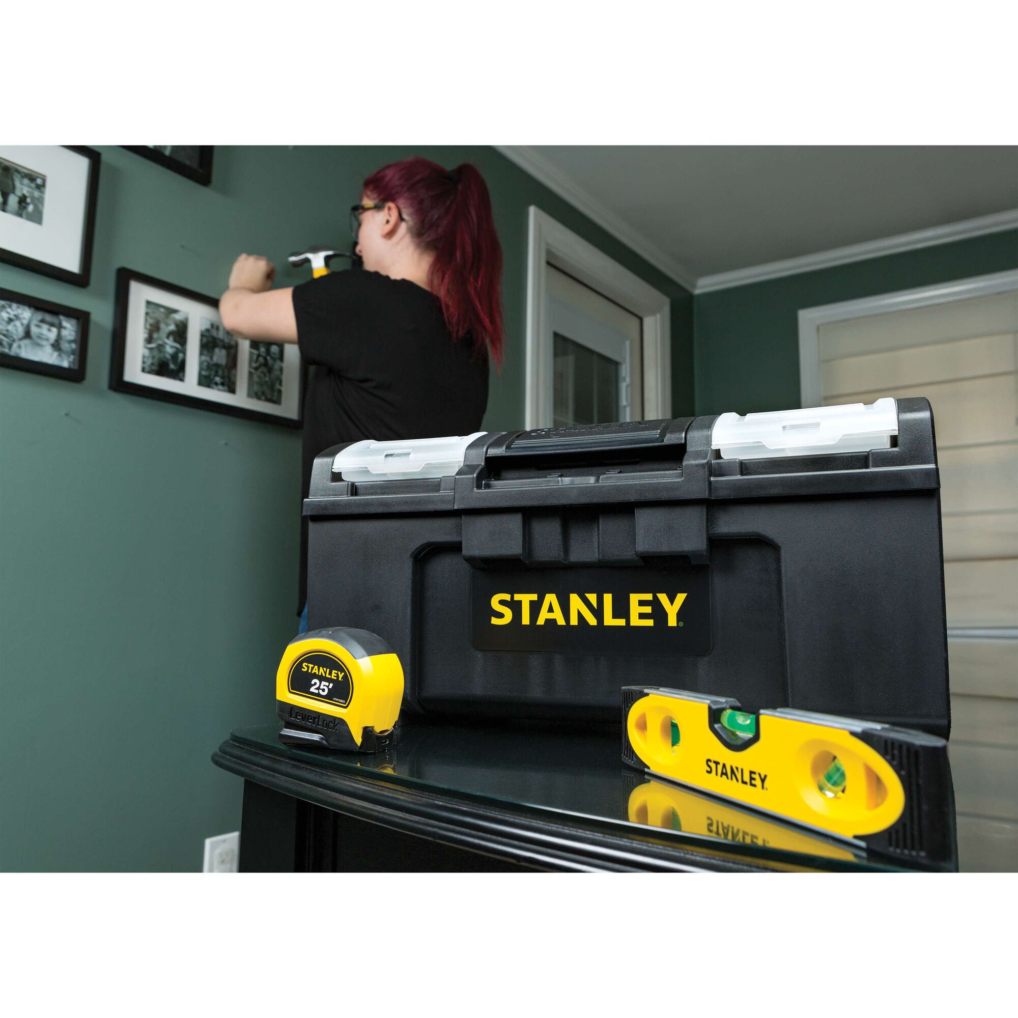 STANLEY STST19420 black toolbox with yellow logo, tape measure, and level on table in a home interior.